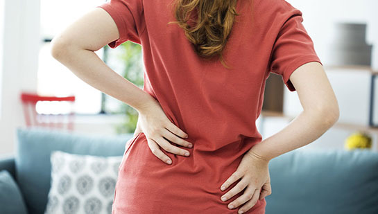 Mujer sosteniendo la parte baja de la espalda con dolor antes de visitar al quiropráctico Phoenix