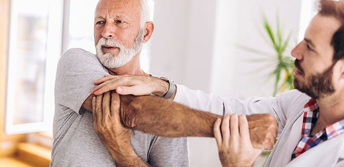 Elderly man receiving shoulder adjustment from Laveen chiropractor