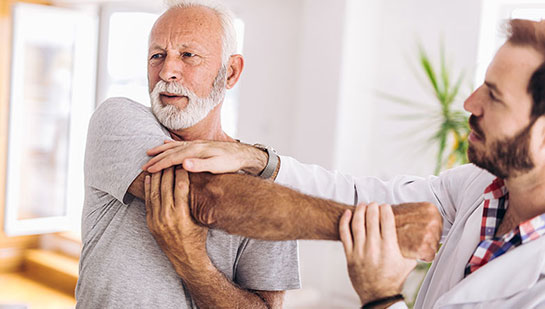 Elderly man receiving shoulder adjustment from Laveen chiropractor